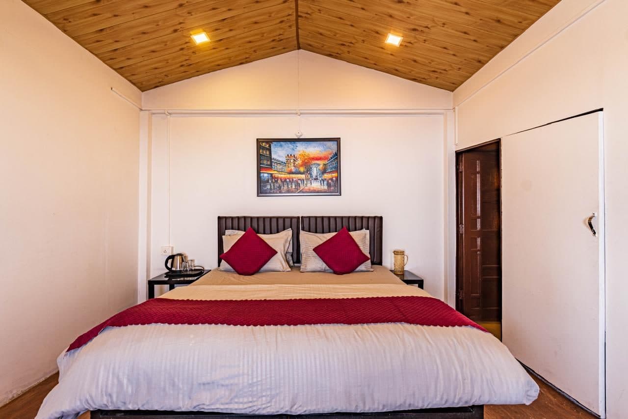 Spacious bedroom at Spandan Villas with king bed, timber ceiling, and red cushions